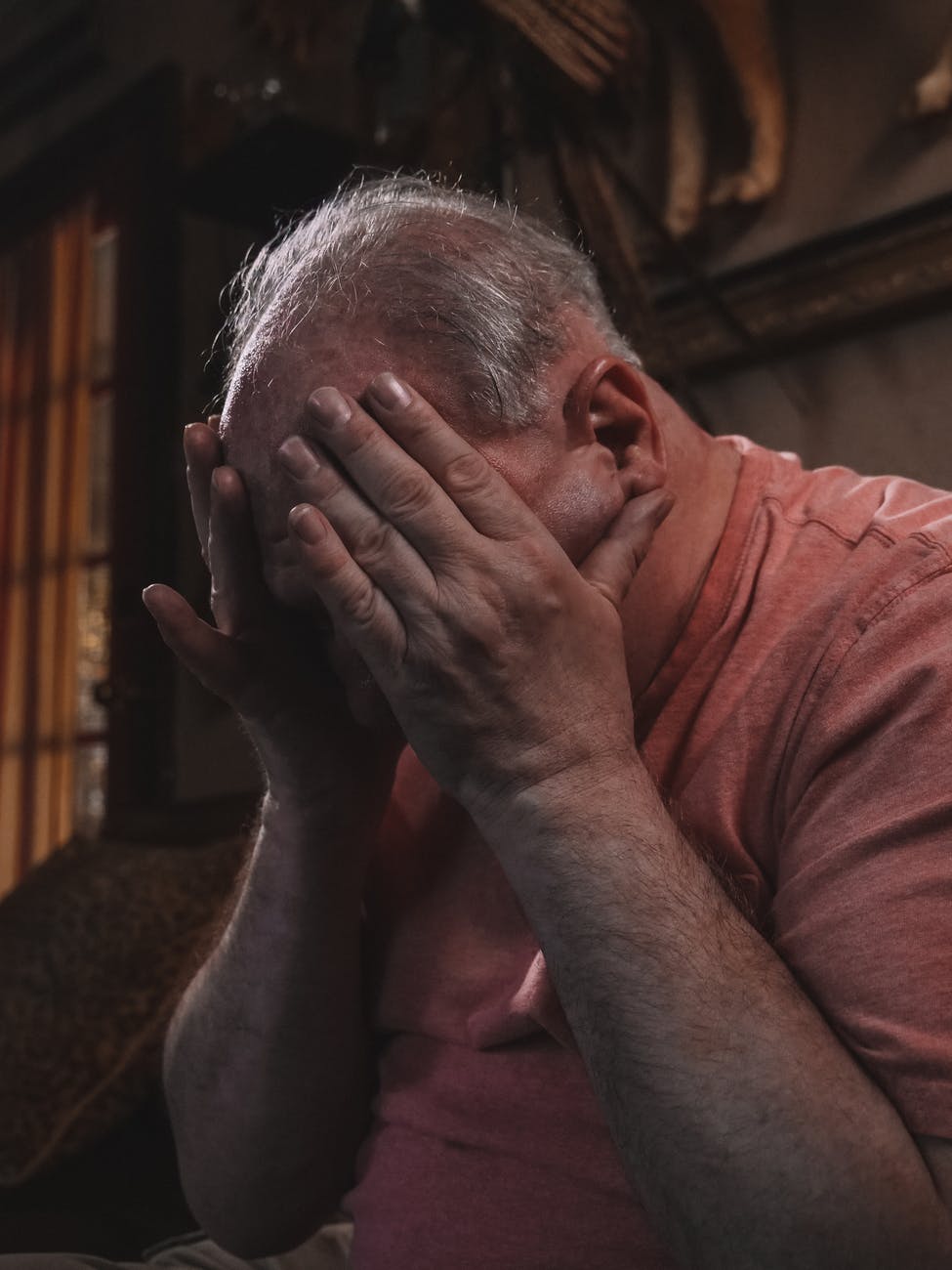 an elderly man with his hands on his face